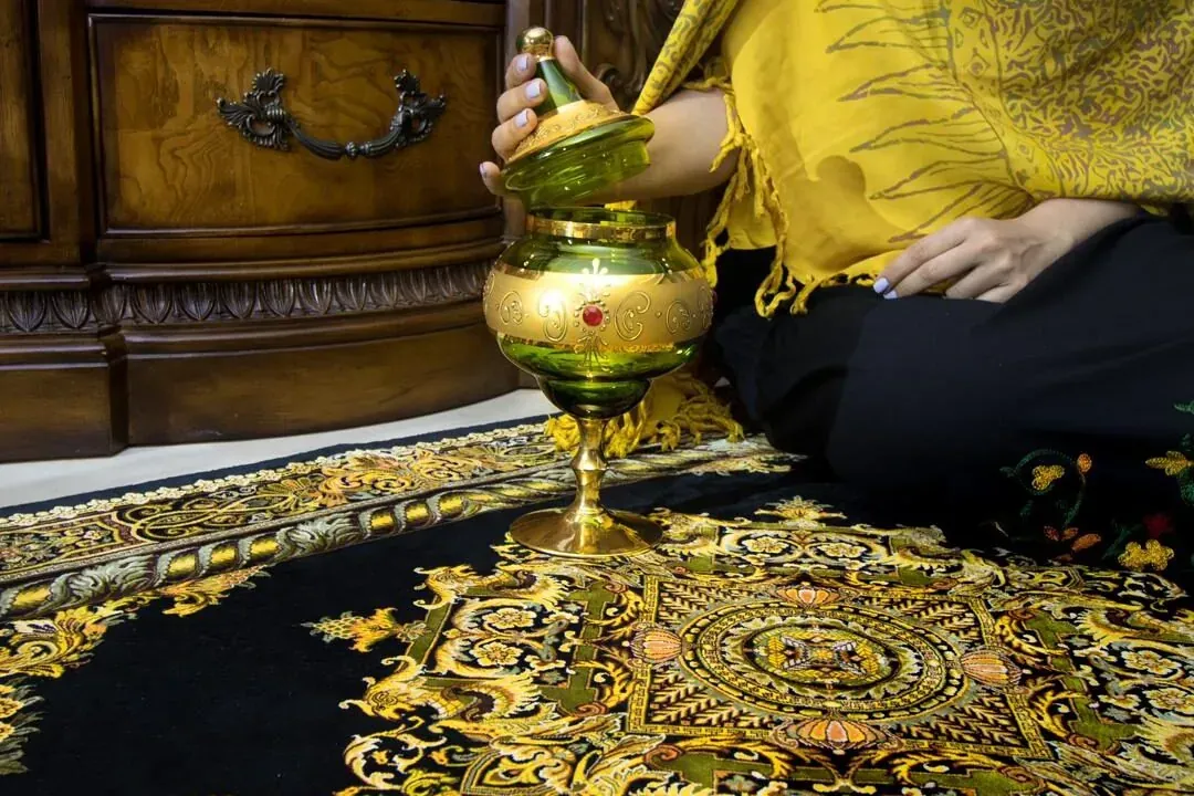 Black and gold silk rug with a hand-painted glass vase